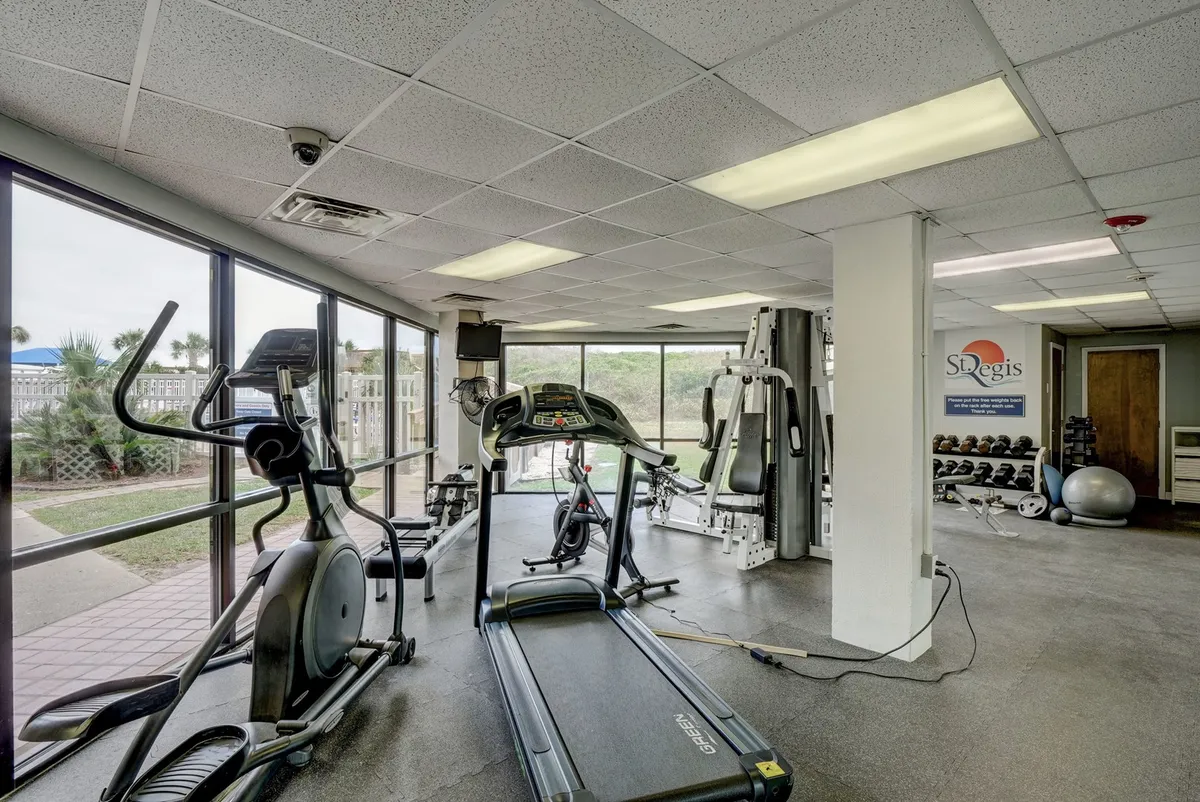A bright and spacious fitness center featuring a treadmill, exercise bike, and weight machines. Large windows let in natural light and offer views of the outdoors, creating an energetic and inviting space for workouts.