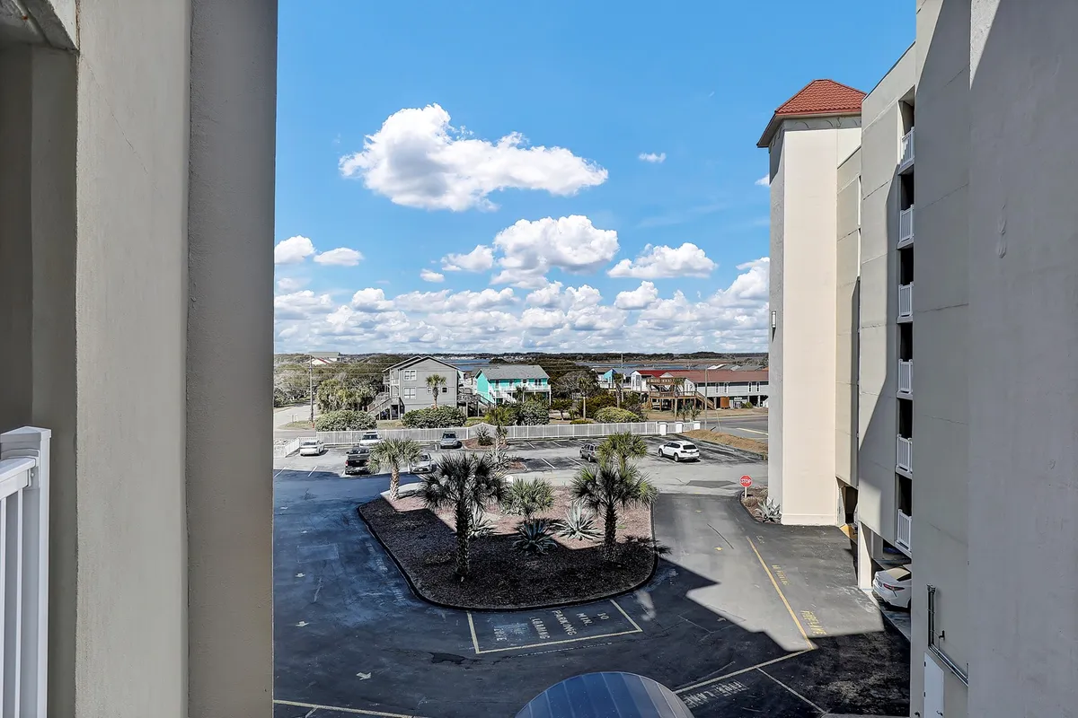 A relaxed street view featuring clouds, palm trees, and colorful houses. The image captures the ambiance of the neighborhood and suggests opportunities for strolling, enjoying the scenery, and taking in local sights after work or during wellness breaks.