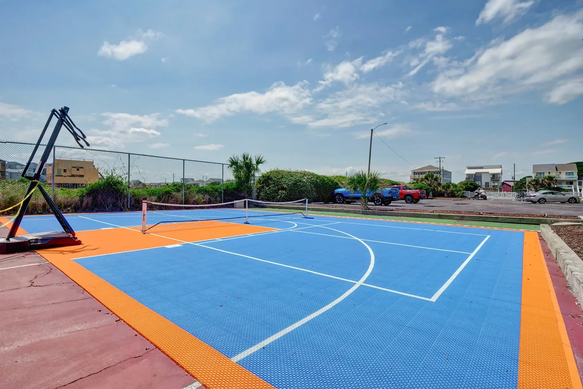 An exterior view of multi-purpose courts with a basketball hoop, tennis net, and colorful court surface, inviting guests to engage in friendly competitions or casual games outdoors.